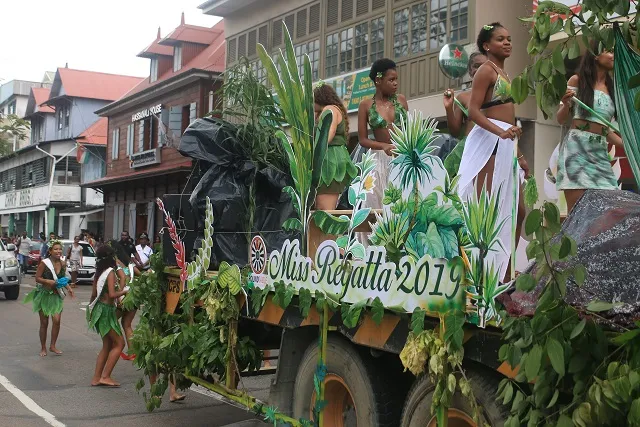 Char décoré et participantes en costumes lors d'un défilé du Festival Kreol à Victoria