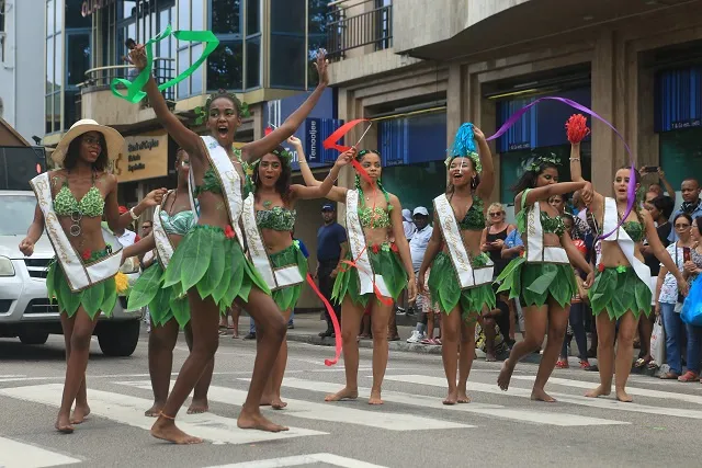 Danseuses en costumes de feuilles défilant dans une rue de Victoria pendant le Festival Kreol
