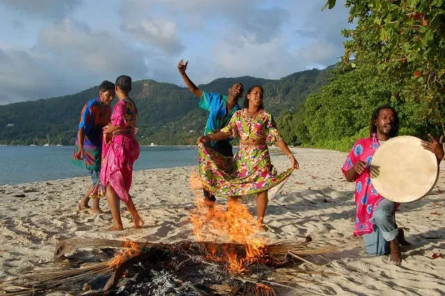 Danseuses et joueur de tambour lors d'un moutya autour d'un feu sur une plage des Seychelles